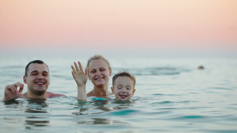 Family-of-three-waving-with-hands-from-the-sea