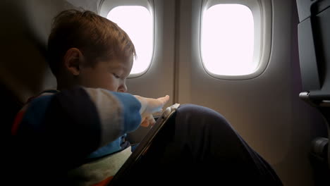 Kleiner-Junge-Spielt-Im-Flugzeug-Auf-Dem-Touchpad