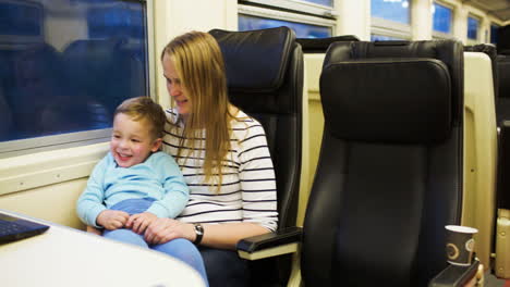 Mother-with-child-enjoying-video-on-laptop-in-the-train