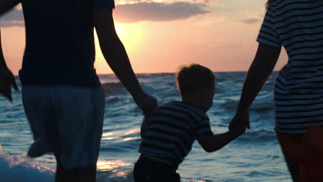 Happy-family-of-three-dancing-by-sea-at-sunset