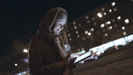 Woman-with-touch-pad-typing-on-her-way-in-night-city