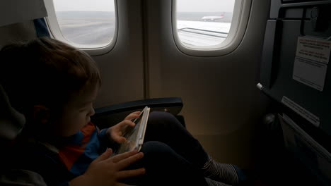 Boy-using-tablet-PC-in-plane-going-to-take-off