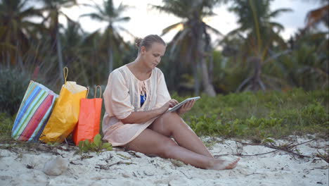Mujer-Después-De-Ir-De-Compras-Usando-Tablet-Pc-En-La-Playa