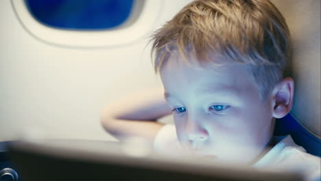 Little-boy-using-tablet-computer-during-flight