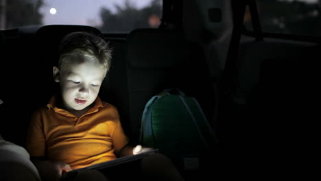 Kleiner-Junge-Benutzt-Tablet-PC-Während-Der-Autofahrt-In-Der-Nacht
