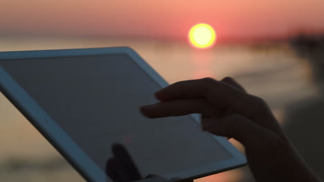 Woman-hands-typing-on-pad-outdoor-at-sunset
