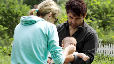 Young-parents-feeding-a-baby-boy-outdoor