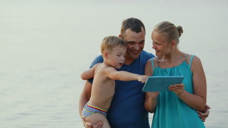 Parents-and-little-son-with-pad-by-the-sea