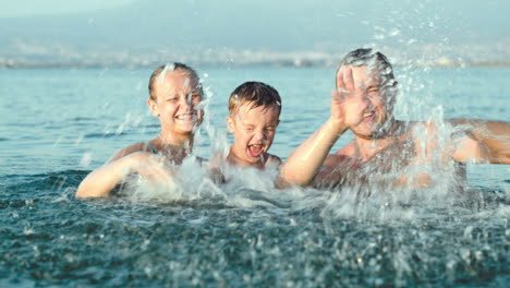 Family-of-three-splashing-water-in-sea