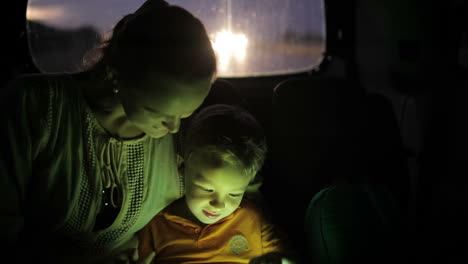 Niño-Usando-Tablet-Pc-Durante-El-Viaje-En-Automóvil-Por-La-Noche