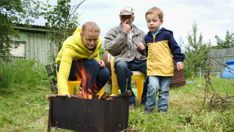 Mother-son-and-grandpa-by-fire-in-the-yard