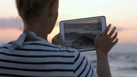 Woman-making-photos-of-sea-waves-with-pad