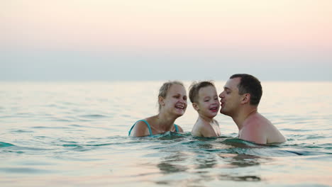 Happy-family-of-three-bathing-in-sea