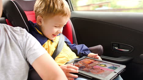 Happy-boy-playing-game-on-pad-during-car-travel
