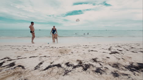 Happy-family-of-three-playing-a-ball-on-the-beach