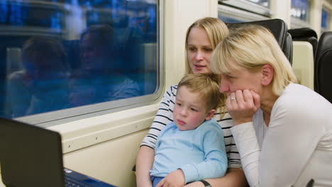 Family-with-child-in-the-train-watching-video-on-laptop