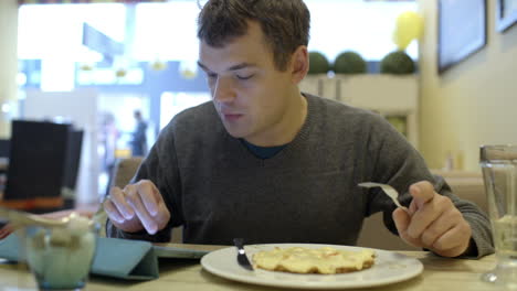 Man-using-pad-and-having-dinner-in-cafe