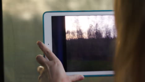 Woman-with-pad-in-the-train-making-a-video-of-passing-landscape