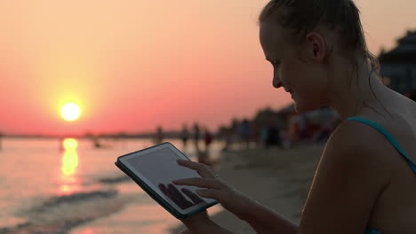 Happy-woman-with-pad-on-beach-at-sunset