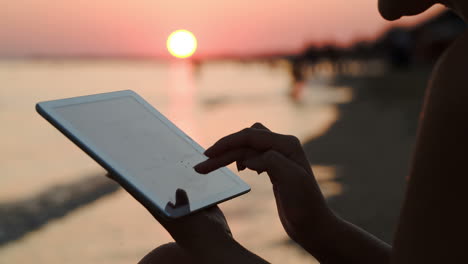 Mädchen-Arbeitet-Mit-Tablet-PC-Am-Strand-Bei-Sonnenuntergang