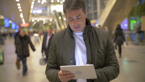 Man-using-digital-tablet-in-airport-hall