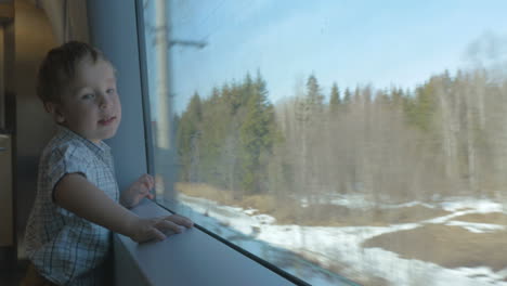 Boy-looking-at-nature-scene-through-the-train-window