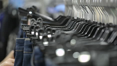 Woman-in-the-store-choosing-jeans-hanging-on-racks