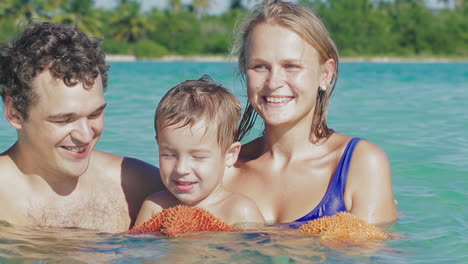 Parents-and-their-little-son-in-sea-water-holding-starfish