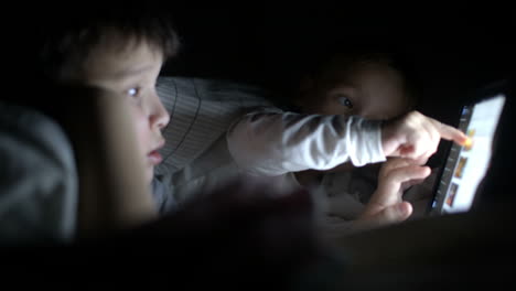 Zwei-Kleine-Jungen-Versuchen,-Den-Film-Nachts-Mit-Einem-Tablet-Anzusehen