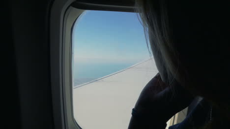 Frau-Schaut-Im-Flugzeug-Aus-Dem-Fenster