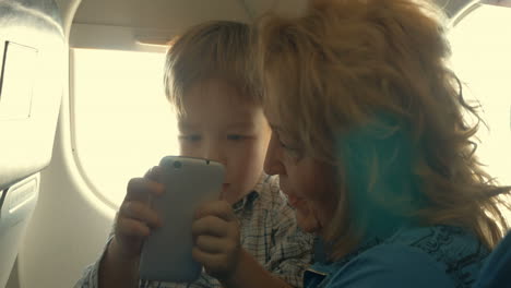 Kind-Und-Großmutter-Unterhalten-Sich-Im-Flugzeug-Mit-Dem-Telefon