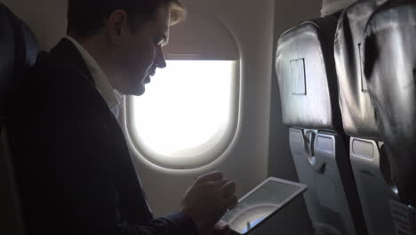 Young-businessman-working-with-pad-in-plane