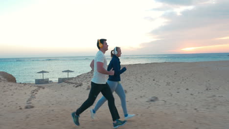Young-people-jogging-on-the-beach-at-sunset