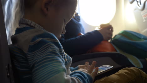 Kleines-Kind-Im-Flugzeug-Mit-Smartphone