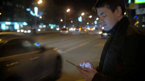 Man-using-touch-pad-by-the-busy-road-in-city