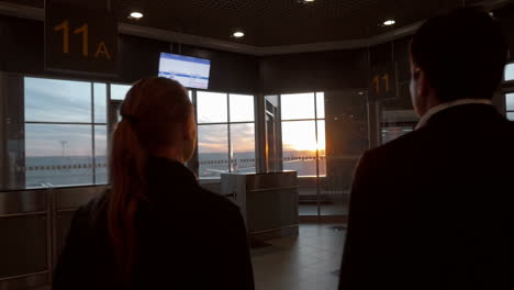 Man-and-woman-enjoying-sunset-through-airport-window