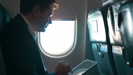 Man-using-tablet-computer-during-the-flight
