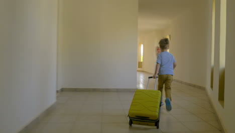 Child-with-rolling-bag-running-along-the-hotel-corridor