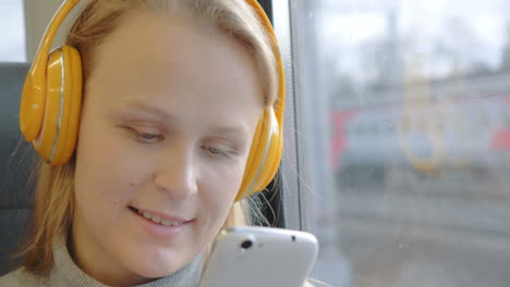 Woman-using-cell-and-listening-to-music-in-the-train