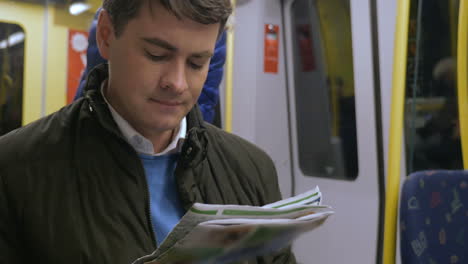 Commuter-spending-time-with-newspaper-in-underground-train
