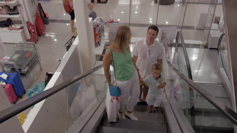 Young-family-with-child-riding-escalator-in-shopping-center