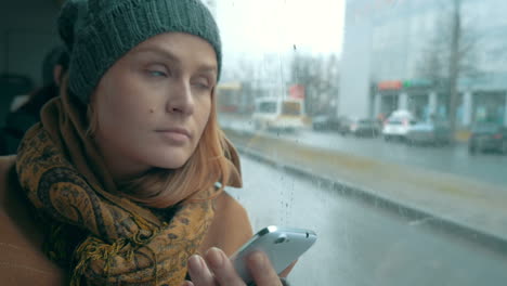 Woman-using-phone-in-bus-on-rainy-day