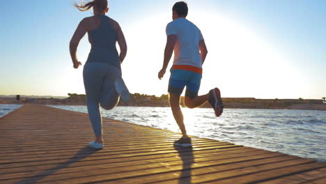 Young-people-jogging-on-the-pier-at-sunset