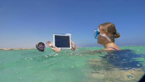 Woman-and-man-in-the-sea-making-vacation-photos-with-pad