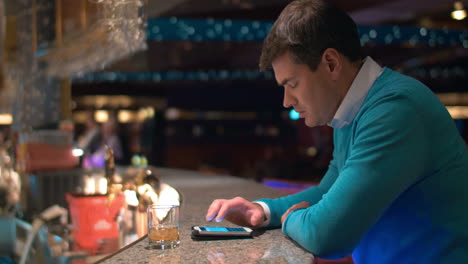 Young-man-typing-sms-on-cell-in-the-bar