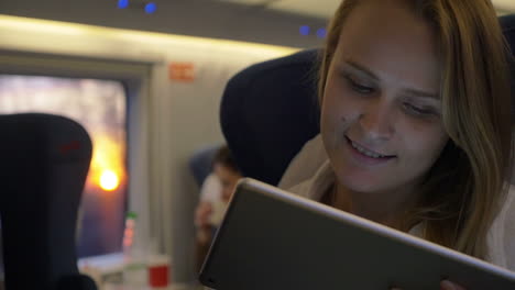 Smiling-woman-with-touch-pad-in-express-train