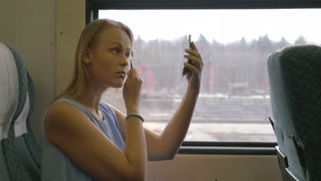 Young-woman-putting-make-up-in-train