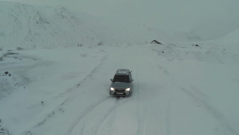 Car-on-Snow-Covered-Road-in-Mountains-Bird-Eye-View