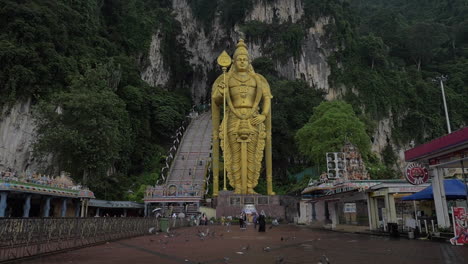 Slow-motion-clip-of-flying-doves-on-foreground-and-Murugan-gold-statue-against-rock-wall-Gombak-Selangor-Malaysia