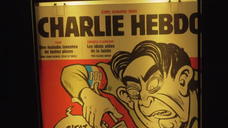 Straßenbanner-Des-Satirischen-Magazins-Charlie-Hebdo-In-Der-Nacht-Von-Paris,-Frankreich